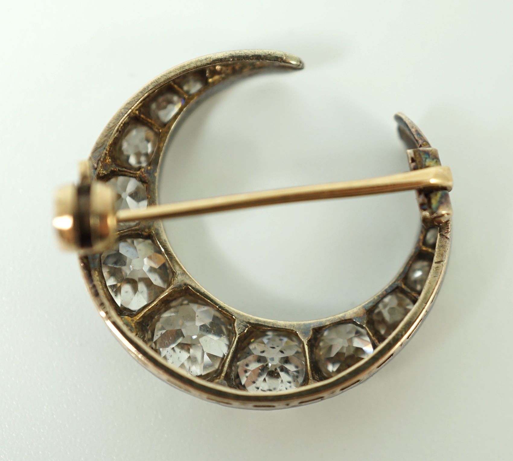 A Victorian gold, silver and graduated thirteen stone diamond set crescent brooch